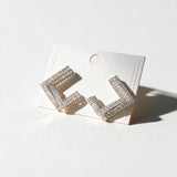 Silver tone open square earrings set with clear baguette crystals on a white card