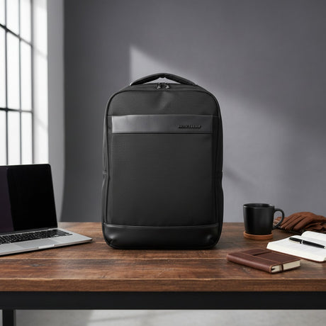 Black backpack on a wooden desk with a laptop and coffee mug in a modern office setting
