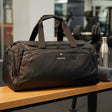 Black duffel bag with 'WEPower' branding on a wooden surface in a gym setting