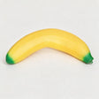 Curved yellow banana squishy with green tips on a light grey background