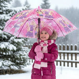 Girl in snow holding an open pink Barbie kids umbrella with a doll print canopy