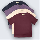 Four tshirts in black, purple, beige, and maroon on a light gray background