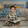 Child in Batman pajamas reading a book in a bedroom with matching bedding