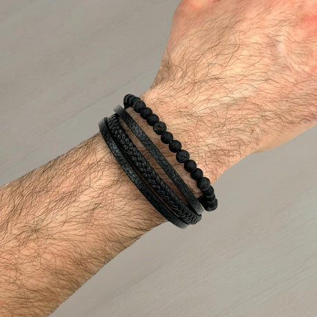Black lava bead and braided leather bracelet stack worn on a wrist