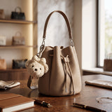 Taupe drawstring bucket bag with a leather drawstring and bear charm