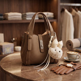 Taupe pebbled handbag with a silver twist lock and bear charm