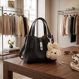 Black pebbled handbag with a silver twist lock and teddy bear charm
