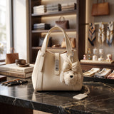 Cream pebbled handbag with a twist lock and fluffy bear charm