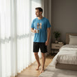 Bear print pyjama set worn holding a mug by a bedroom window