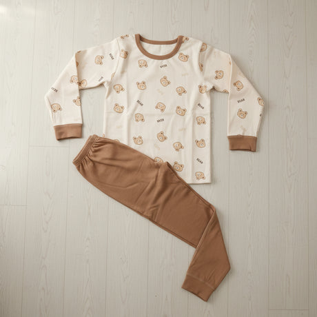 Cream teddy bear print pyjama top with tan joggers laid flat on a wood floor