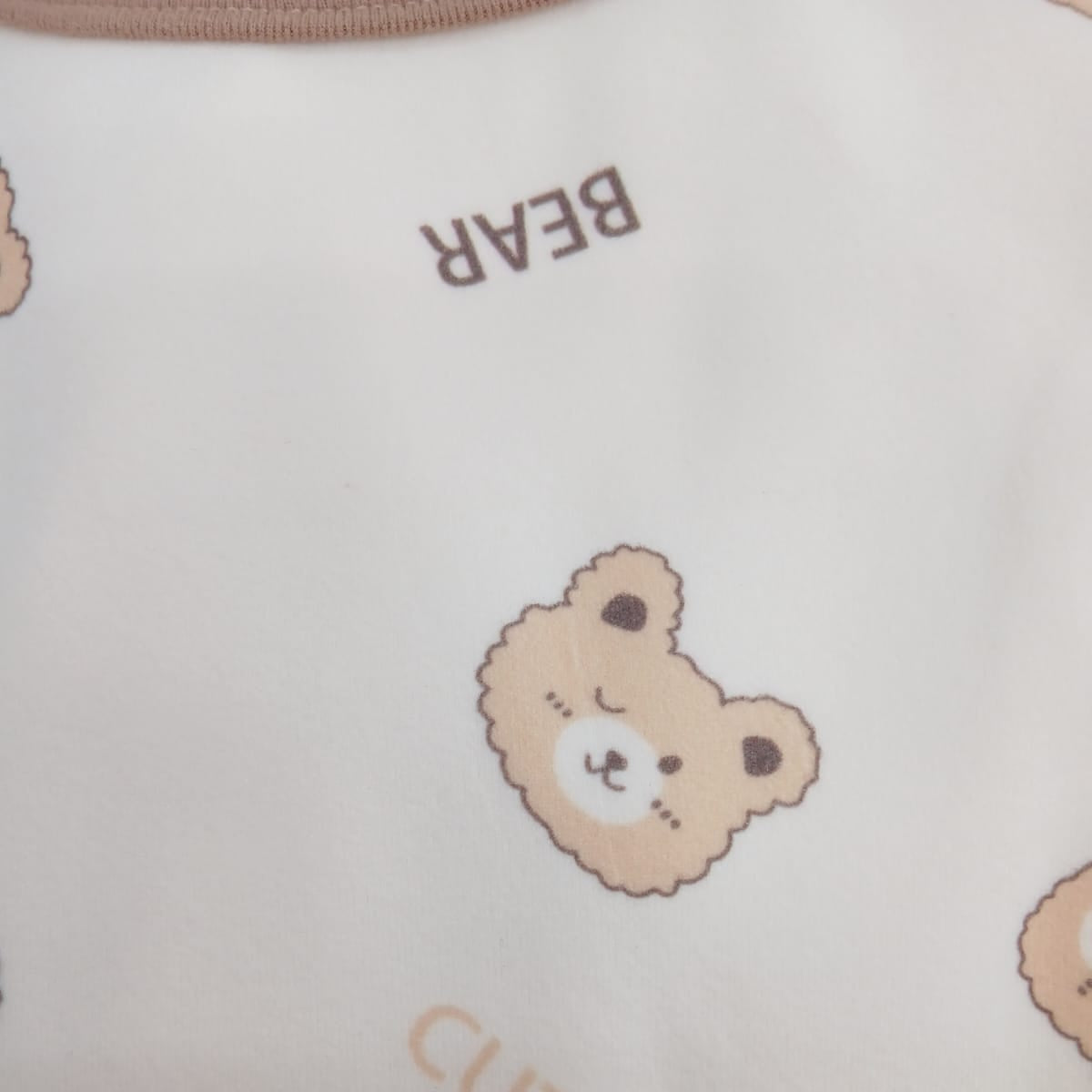 Close up of the teddy bear face print with BEAR lettering on cream pyjama fabric