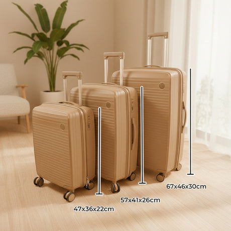 Beige suitcase set with handles up beside a plant in a warm room