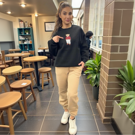 Woman pointing at a black sweatshirt with a graphic bear design in a casual setting