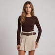 Beige box pleated mini skirt with a brown belt and square buckle, worn with a brown knit