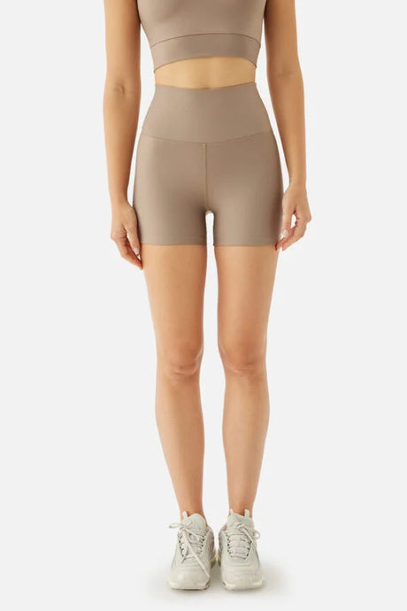 Person wearing beige high-waisted shorts and a matching crop top on a white background