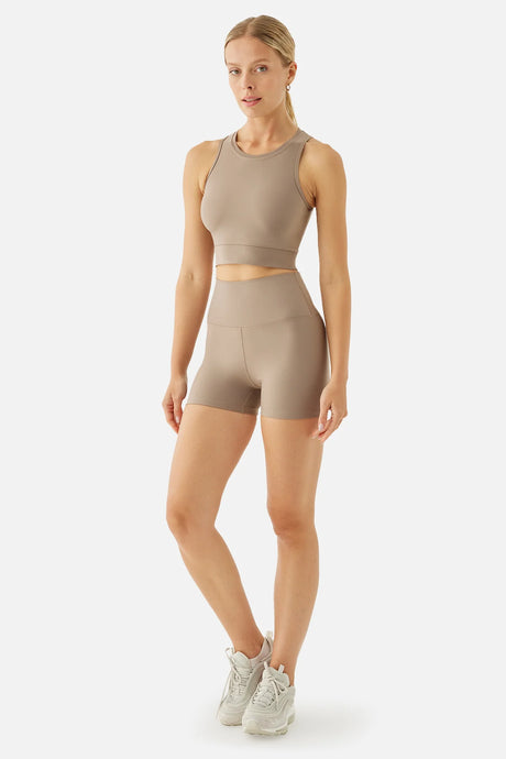 Woman wearing a beige athletic outfit on a white background