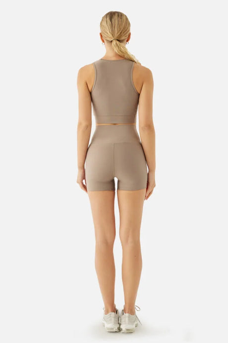 Woman wearing a beige athletic outfit on a white background