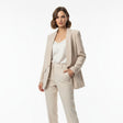 Woman wearing a beige suit with a white top on a white background
