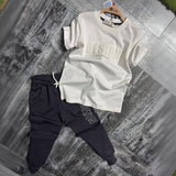 Cream embossed print tee and navy cargo joggers, boys two piece set laid flat