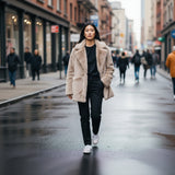 Woman walking on a city street wearing a beige fur coat and black pants