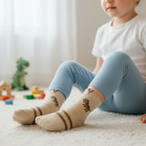 Beige dinosaur knee high socks with brown stripe cuff worn on a rug