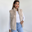 Beige faux fur sleeveless gilet with stand collar and gold zip over a white long sleeve top