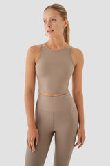 Woman wearing a beige sleeveless top and leggings on a light grey background