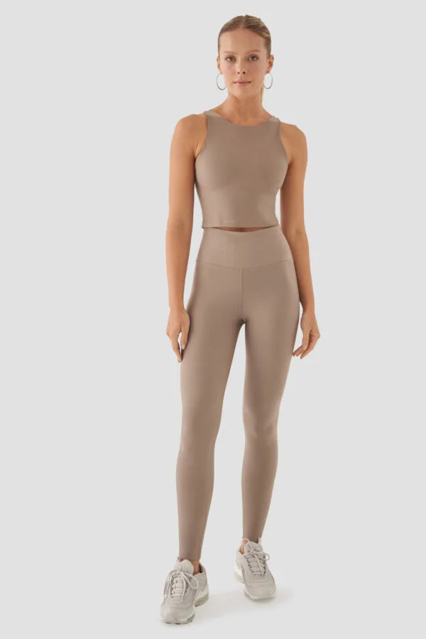 Woman wearing a beige tank top and leggings set on a white background
