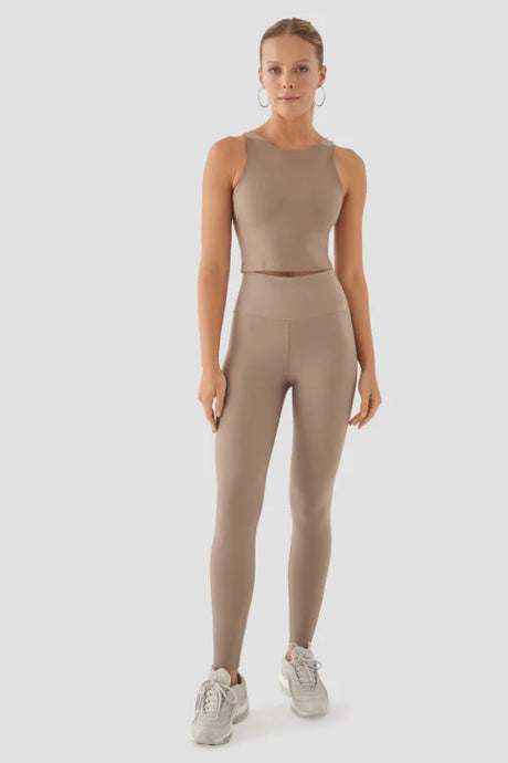 Woman wearing a beige tank top and leggings set on a white background