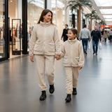 Mother and daughter in matching beige teddy fleece sets walking through a mall