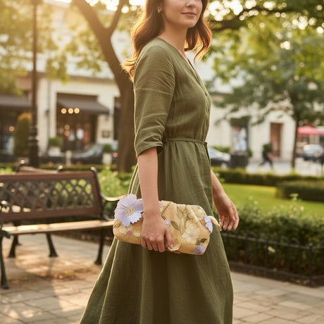 Woman carrying the beige floral embroidered clutch bag in a summer dress