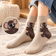 Woman in jeans wearing beige crew socks with a fuzzy brown koala hugging each ankle on a rug