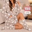 Woman in a beige hooded fleece robe with white hearts, hand in the front pocket, matching socks