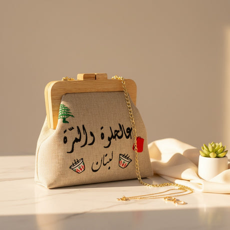Beige linen heritage bag with its gold chain strap pooled beside it on marble