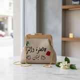 Beige linen frame bag with a wooden clasp, green cedar, Arabic script and a red tarboosh charm
