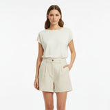 Woman wearing a beige outfits with beige linen shrots on a white background