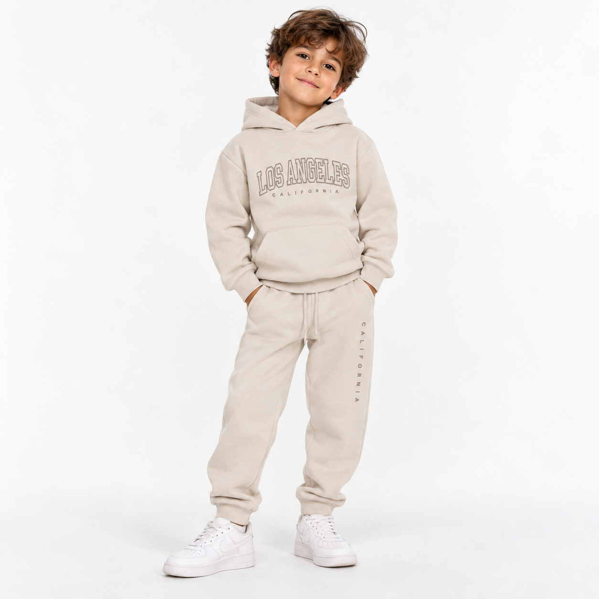 Boy wearing a beige Los Angeles hoodie and matching joggers with white sneakers