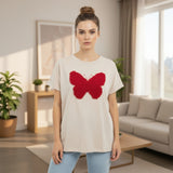 Woman wearing a white tshirt with a red butterfly design in a living room