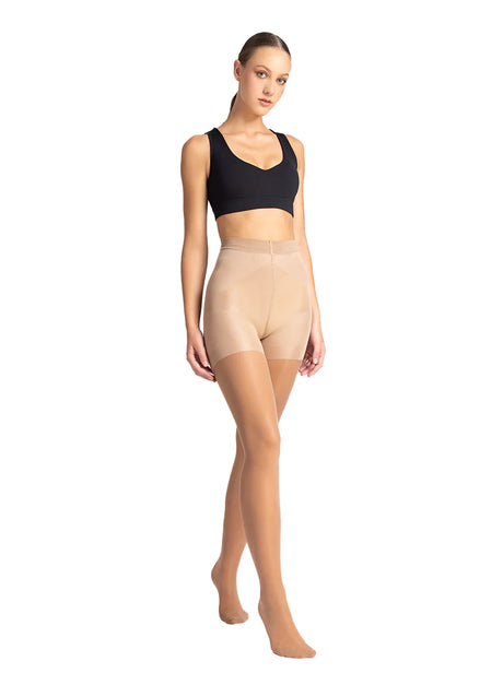 Woman wearing beige shapewear and a black sports bra on a white background