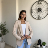 Beige blazer held closed at the front, showing the drape of the open lapel