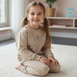 Girl in a beige sequin bow sweatshirt and matching cuffed joggers