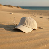Cream cotton summer cap on smooth sand dunes with the sea behind
