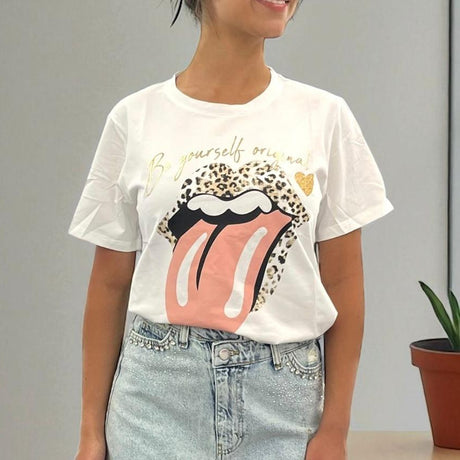 Person wearing a beige tshirt with a graphic design and text, standing against a plain background