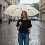 Woman holding a beige umbrella on a rainy street