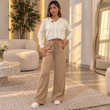 Woman in beige wide leg sweatpants with hands on her hips in a bright living room
