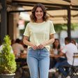 Pastel yellow tee with a Believe in Yourself script worn with blue jeans at a cafe