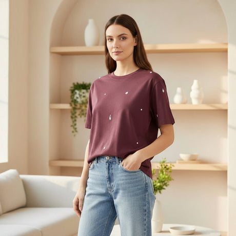 Woman wearing a maroon tshirt with white patterns in a modern living room
