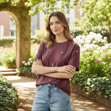 Woman wearing a maroon tshirt with white dots and light blue jeans in a modern living room