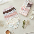 Neutral mix of blush, brown and cream full coverage briefs beside their box and a cup of tea