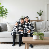 Two kids sitting together in buffalo check hooded blankets